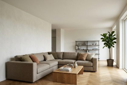 Canapé d'angle en tissu beige dans un salon moderne avec parquet en chêne et table basse en bois