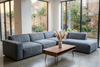 Salon contemporain avec canapé modulaire en lin gris, table basse en noyer et sol en béton poli pour une maison tendance